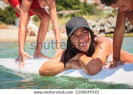 Mom with her two sons lying on a swimming board. Happy european family having fun floating on a swim board in the sea on a hot summer day