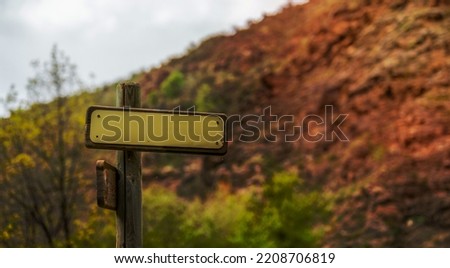 mountain directional sign mockup with spider webs hanging and trees in the background