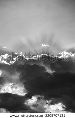Amazing landscape of the sky. Beautiful sun rays bursting out from a cumulus cloud ahead of a storm. Lovely nature landscape. Black and white photo.
