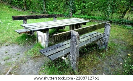 Beautiful old park bench ideal for picnic eating break while hiking in the nature park with green grass in the background in springtime
