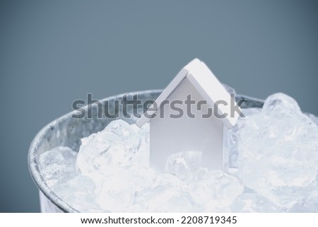 Abstract background, copy space,  miniature house model falling in cold iced cubes bucket. Housing market cooling down concept. Royalty-Free Stock Photo #2208719345