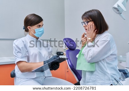 Talking dentist and woman patient in dental clinic