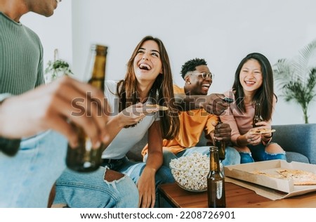 Group of friends watching tv and eating pizza - Multiracial cheerful young people having weekend home party together - Happy students having fun in university rooms - Youth lifestyle and food concept Royalty-Free Stock Photo #2208726901