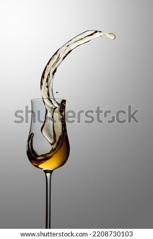 The drink spills out of the glass. Concept of the theme of premium alcohol. Copy space. Royalty-Free Stock Photo #2208730103