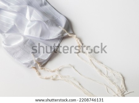 Jewish national and religious tallith katan - in the form of a cape with brushes. Theme of traditions, jewish ritual object. Jewish holiday of Sukkot, shabbat, rosh hashanah. Tallit katan, background Royalty-Free Stock Photo #2208746131