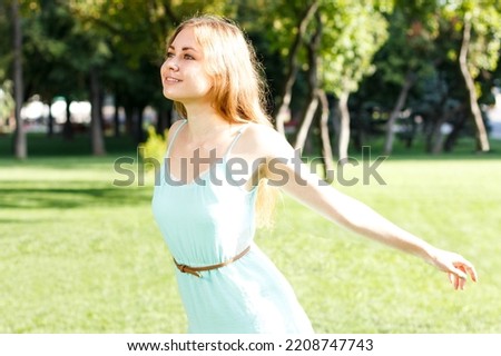 Pretty blondy girl wearing elegant dress relaxing outdoor in green grass and smells aromatic lemon or lime citrus. High quality photo