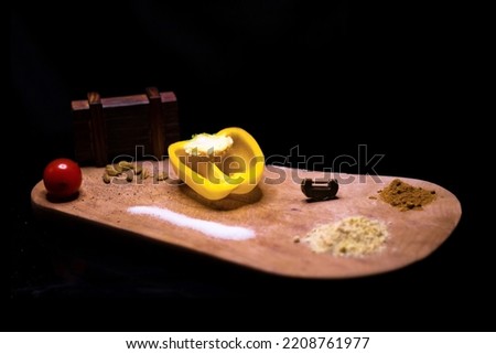yellow bell peppers on a wooden cutting board with spices and a puzzle as decoration with Black background