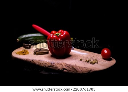 red bell peppers on a wooden cutting board with spices and a puzzle as decoration with Black background