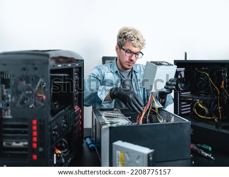 Caucasian young technician repairing inside of desktop computer cabinet. White background