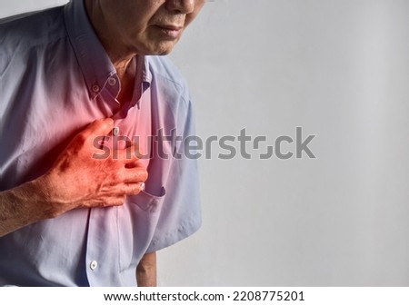 Asian elder man suffering from central chest pain. Chest pain can be caused by heart attack, myocardial infarct or ischemia, myocarditis, pneumonia, oesophagitis, stress, anxiety, etc,. Royalty-Free Stock Photo #2208775201