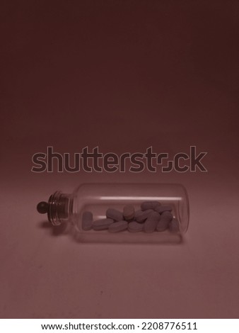 Picture of pills in a clear glass bottle with a purple-red gradient background.