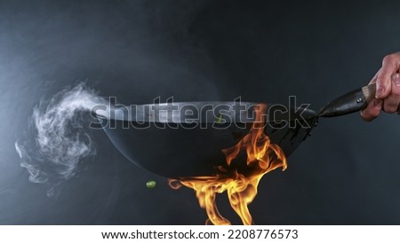 Freeze Motion of Wok Pan with Flying Ingredients in the Air and Fire Flames. Royalty-Free Stock Photo #2208776573