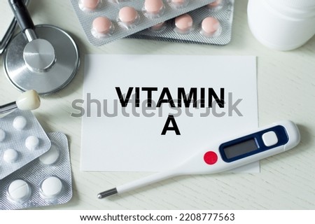 On the table are medicines, a stethoscope, a thermometer and a card with the text vitamin A