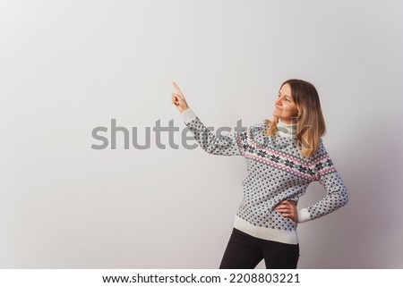 Russian girl in a knitted pullover on a white wall. Slav girl in a Turkish knitted New Year's sweater on a light wall. Christmas sweater with stars on a woman for a photo shoot