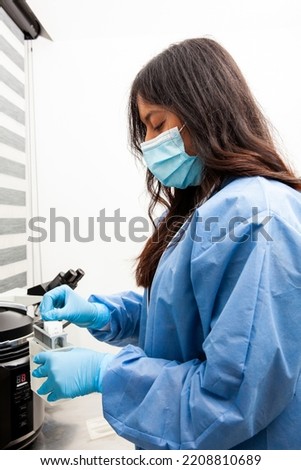 Young female scientist at the Immunohistochemistry laboratory carry out antigen retrieval on microscope slides with biopsy tissue.
