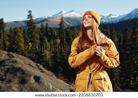 Woman smile with teeth happiness and laughter tourist in yellow raincoat travel in the fall and hiking in the mountains in the sunset sunshine freedom