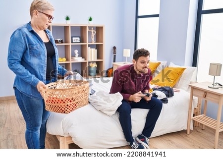 Mother and son doing laundry and playing video game at bedroom