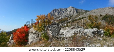 Panoramic view of the mountain range, rocks and trees, bright autumn colors. The peak 'Eklizi-Burun' is one of the highest peaks of the Crimean peninsula in the autumn sunny day.