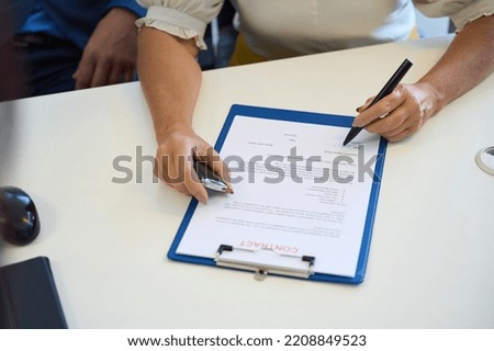 Buyer in the car dealership signs documents on the purchase of a car