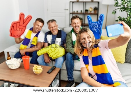 Group of middle age friends watching and supporting soccer match  make selfie by the smartphone at home.