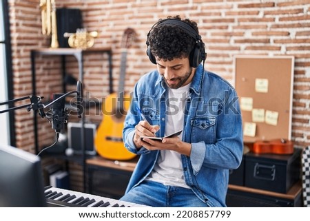 Young arab man musician composing song at music studio