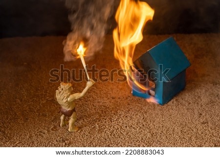 A monster with a torch stands in front of a burning blue house. The concept of rebellion. Background picture.