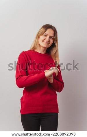 Russian girl in a knitted sweater on a white wall. Slav girl in a knitted New Year's pullover on a light wall. Christmas red sweater on a woman for a New Year's photo shoot