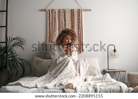 Woman sitting on bed and drinking coffee Royalty-Free Stock Photo #2208895155