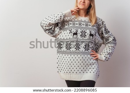 girl in a knitted sweater with deer. Slav girl in a knitted New Year's pullover with animals on a light wall. Christmas sweater on a woman for a New Year's photo shoot