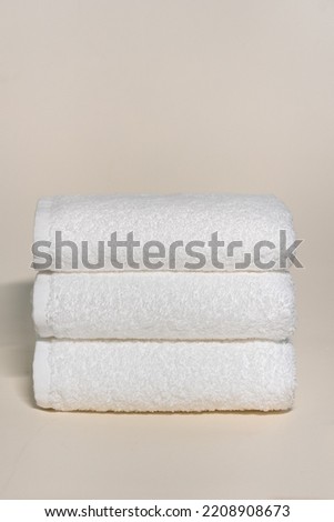 Folded white bathroom towel on beige background. Stack of clean soft towels. Brand New Hotel Spa Cotton Soft Beautiful Design Kitchen Towels. three Piece 100 Cotton Ultra Absorbent Terry Hand Towel.
