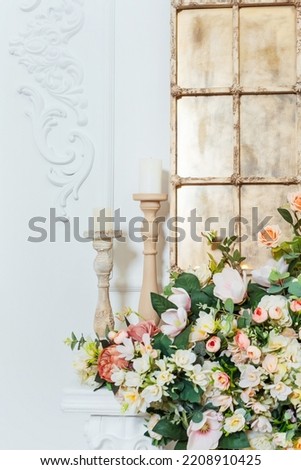 floral decoration on a white fireplace. chandeliers in a classic room in a photo studio. part of the decor with a golden mirror for a photo shoot of weddings