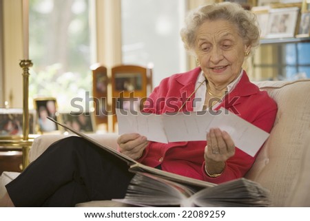 Happy senior woman at home holding a group of photos Royalty-Free Stock Photo #22089259