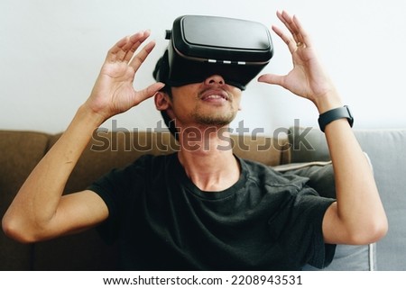 portrait of a young Asian man using virtual reality simulator headset at home.