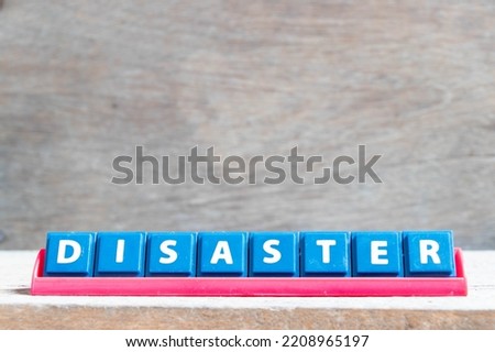 Tile alphabet letter with word disaster in red color rack on wood background