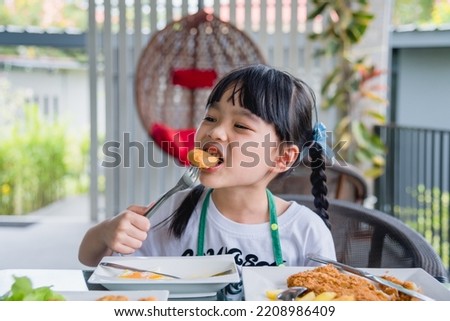Asian young girl Eating Chicken nuggets fast food on table.