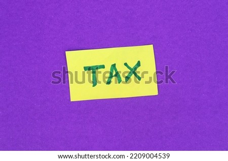 Tax Word Written Yellow Paper Note Isolated on Blue Background, Business and Financial Concepts