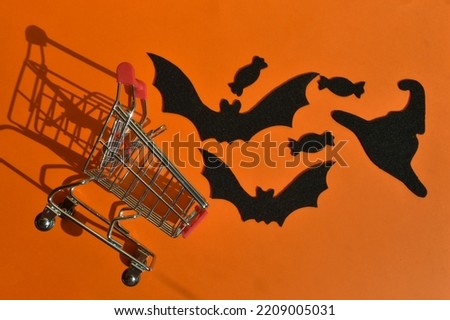 preparation for the Halloween holiday. bat and candy and felt on an orange background. shopping cart. autumn.