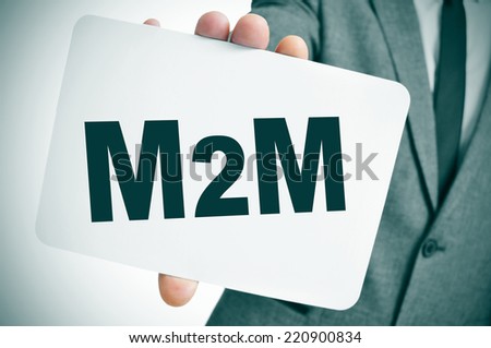 a businessman showing a signboard with the text M2M, for the machine to machine technologies, written in it Royalty-Free Stock Photo #220900834