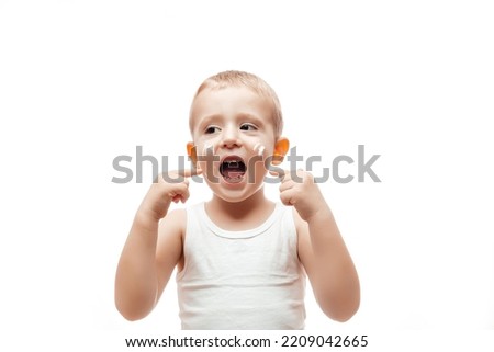 Portrait of cute little caucasian boy applying winter cream for protect skin on white background. concept cleaning wipe, pure, clean.