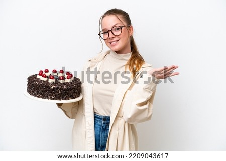 Young caucasian woman holding a Birthday cake isolated on white background extending hands to the side for inviting to come