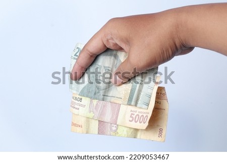 Man's hand showing rupiah banknotes Isolated on white background.