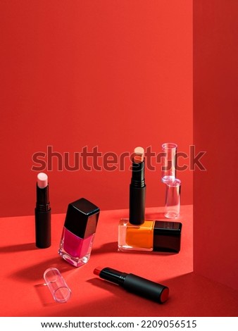 Composition with makeup products. Lipstick and nail polish. Cosmetic products advertisement on red background with Hard light. Product Advertising environment. Sale of beauty products concept.