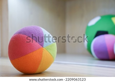 Rainbow soft football pillow for kids in the kindergarten preschool classroom. Multicolor soccer ball toy for decorated in children's bedroom. Toys background with copy space. Selective focus. Royalty-Free Stock Photo #2209063123