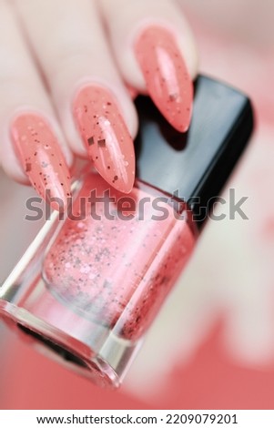 Female hands with long nails and coral orange nail polish