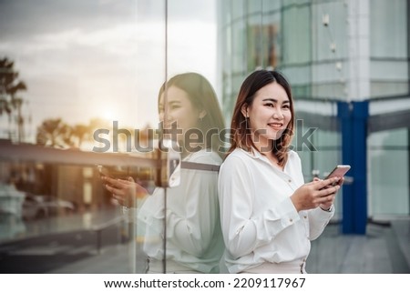 Young Asian businesswoman talking on phone and walking in airport before business trip. Beautiful woman passenger has mobile call and discusses something with smile, holds coffee in hand