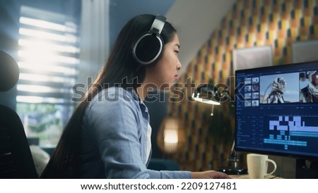 Asian woman in headset editing video with astronauts for client in program on personal computer while working at the table from home office. Freelance