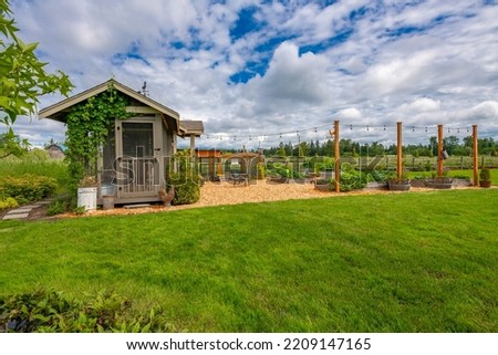 Exterior of estate style home on large landscaped lot with winding driveway expansive patio chicken coop and gardens full of flowers Royalty-Free Stock Photo #2209147165