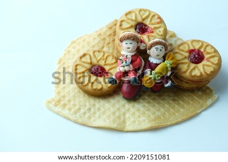 small santa claus decoration made of polymer clay put on waffle with some strawberry cake on white background.