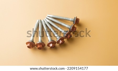 Tapping screws made of steel on orange background, metal screw, iron screw, chrome screw, screws as a background, wood screw, concept industry. High quality picture. Copy space for text.