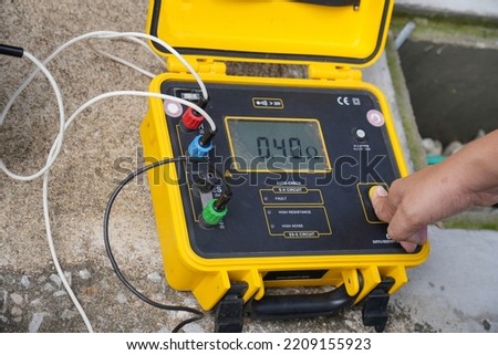 Technician is using a tester to measure electrical ground. Earth resistance tester.